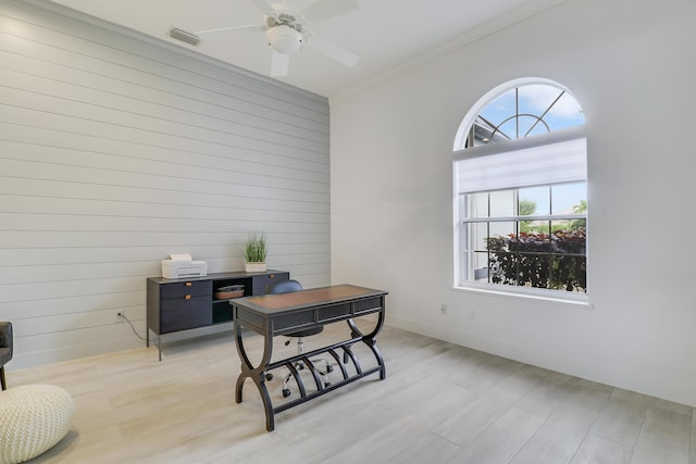 office area with wooden walls, baseboards, light wood-type flooring, and a ceiling fan