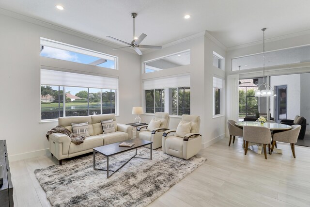 living room with ceiling fan with notable chandelier, ornamental molding, recessed lighting, light wood finished floors, and baseboards