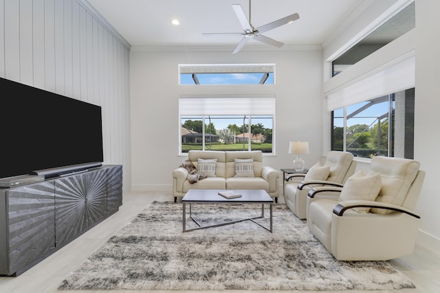 living room featuring plenty of natural light, a towering ceiling, ornamental molding, and a ceiling fan