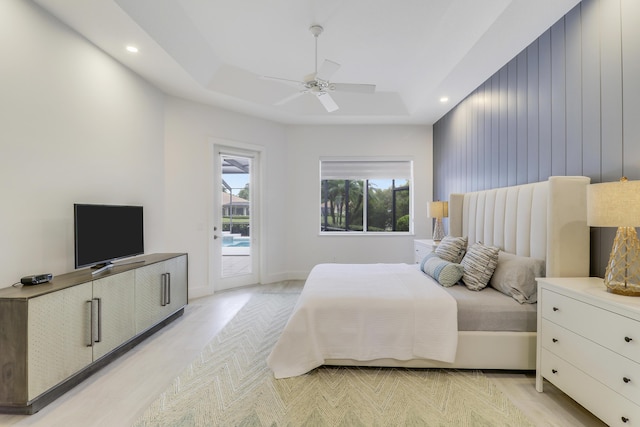 bedroom with access to outside, a raised ceiling, and recessed lighting