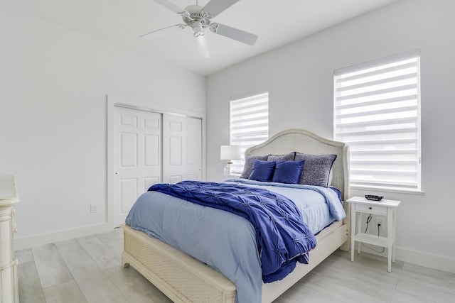 bedroom with a closet, baseboards, light wood-type flooring, and ceiling fan