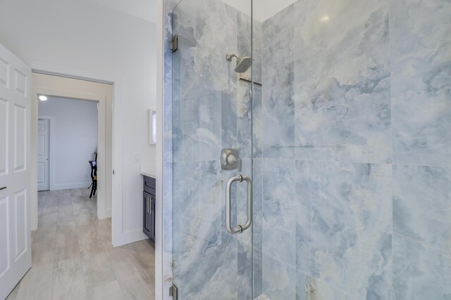 bathroom featuring a marble finish shower, baseboards, vanity, and wood finished floors