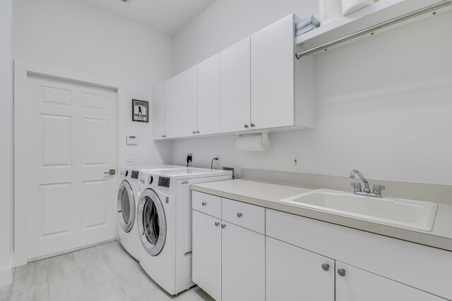 laundry area featuring washer and dryer, a sink, and cabinet space
