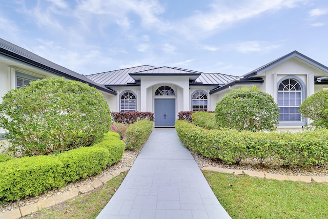 view of front of property with a standing seam roof, metal roof, and stucco siding