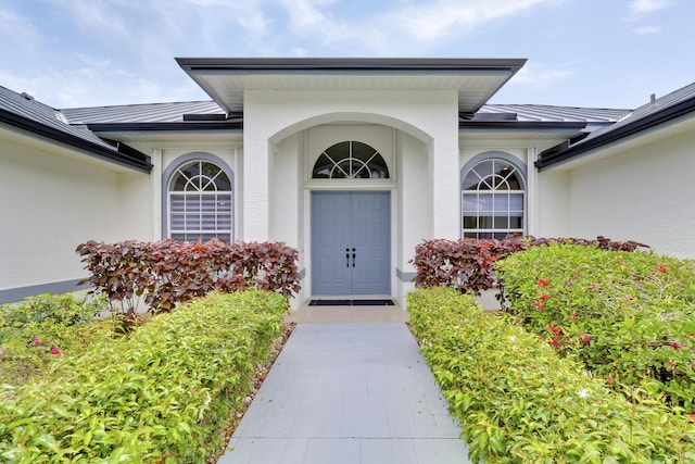 entrance to property featuring a standing seam roof, stucco siding, and metal roof