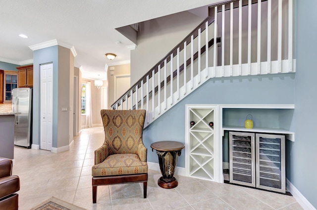interior space featuring crown molding, light tile patterned floors, stairs, wine cooler, and baseboards