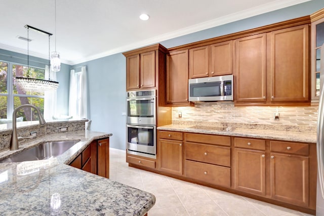 kitchen featuring brown cabinetry, decorative backsplash, a sink, and appliances with stainless steel finishes