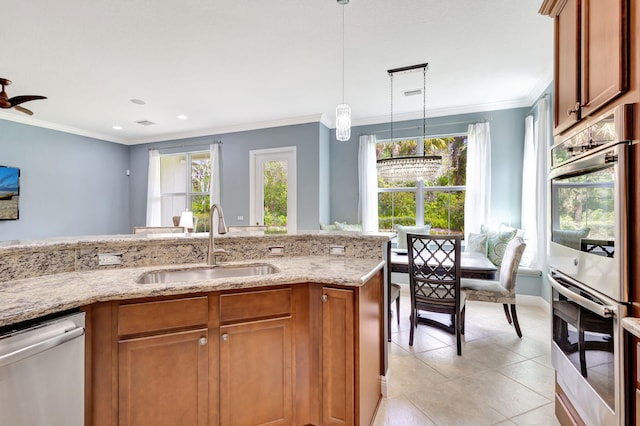 kitchen featuring pendant lighting, a healthy amount of sunlight, a sink, stainless steel appliances, and brown cabinets