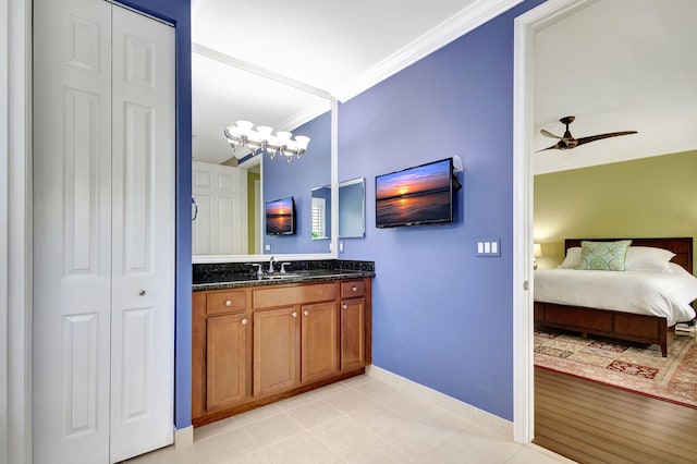 ensuite bathroom featuring a closet, crown molding, vanity, ceiling fan with notable chandelier, and tile patterned flooring