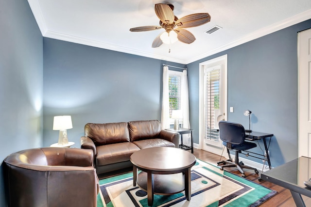 living area with visible vents, baseboards, a ceiling fan, crown molding, and wood finished floors