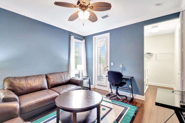 living room with baseboards, a ceiling fan, crown molding, visible vents, and wood finished floors