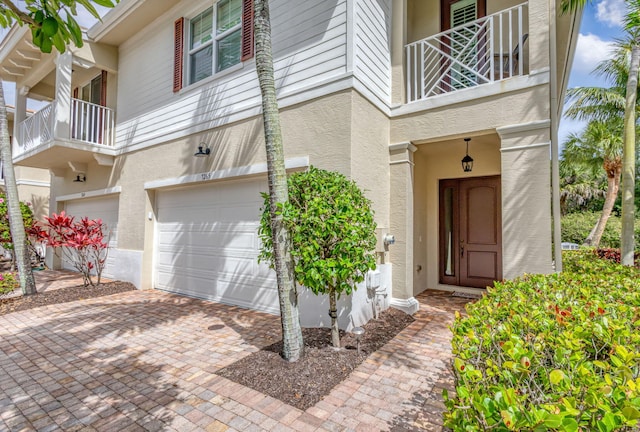 property entrance with a garage, stucco siding, and driveway