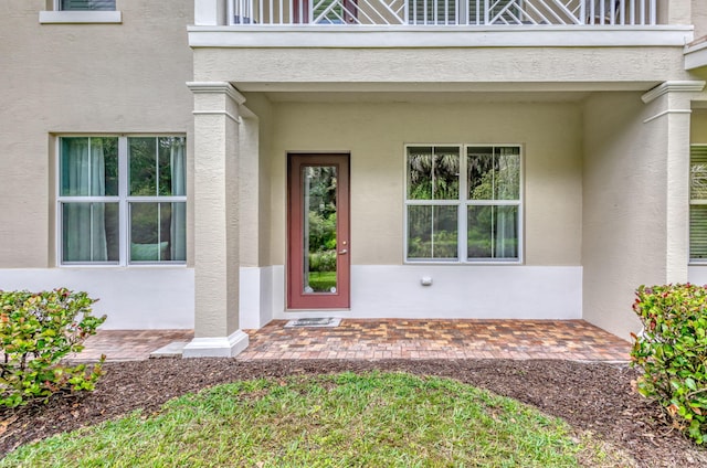 property entrance featuring a balcony and stucco siding