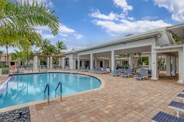 community pool with a patio area and fence