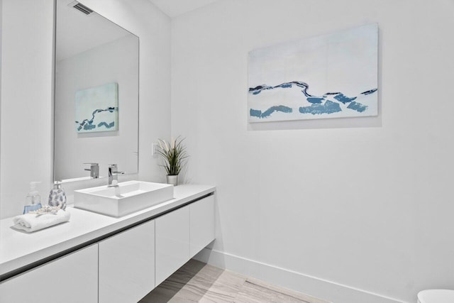bathroom featuring visible vents, baseboards, and vanity