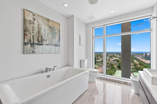 bathroom featuring toilet, a freestanding tub, visible vents, and recessed lighting