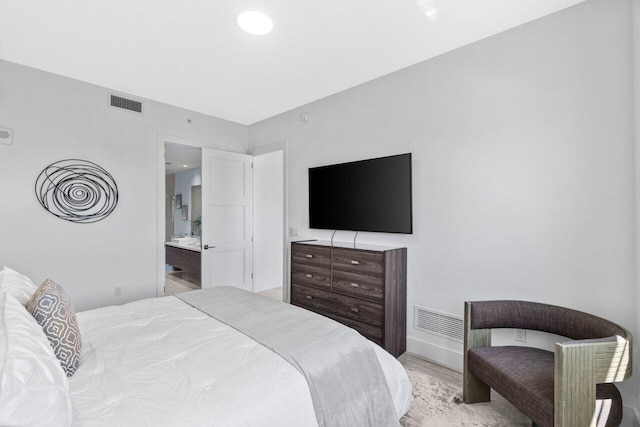 bedroom featuring ensuite bath, light wood-style floors, and visible vents