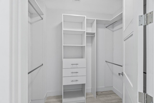 walk in closet with light wood-style flooring