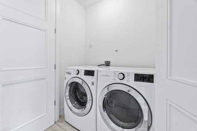 clothes washing area featuring light wood finished floors, washer and clothes dryer, and laundry area