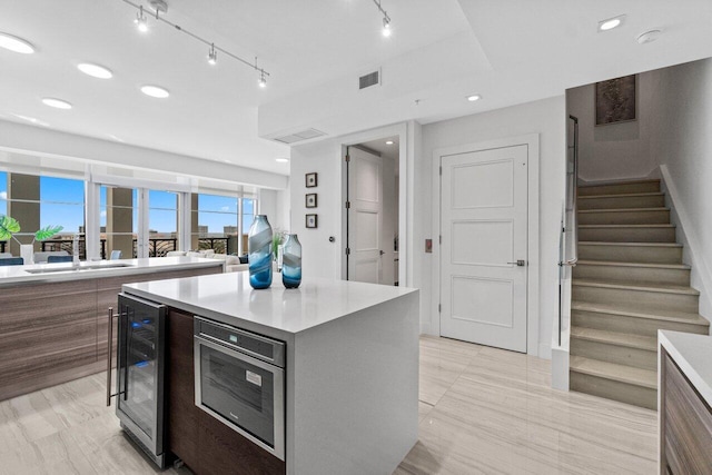 kitchen featuring light countertops, wine cooler, visible vents, and a sink
