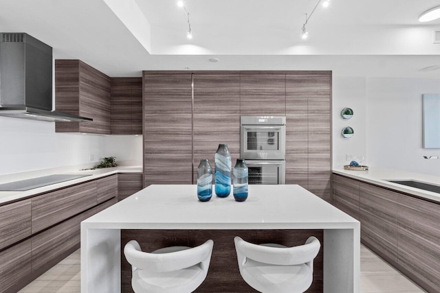 kitchen featuring wall chimney exhaust hood, modern cabinets, and rail lighting