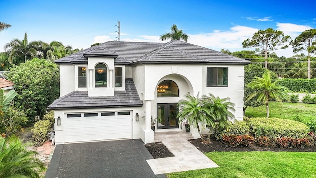 view of front of home featuring a garage, aphalt driveway, stucco siding, and french doors