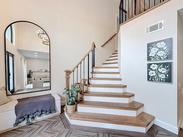 stairway with baseboards, a high ceiling, and visible vents