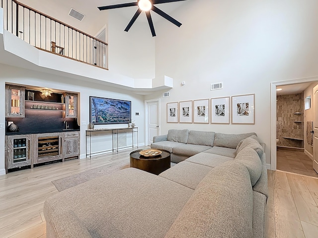 living room with a towering ceiling, ceiling fan, a bar, and visible vents