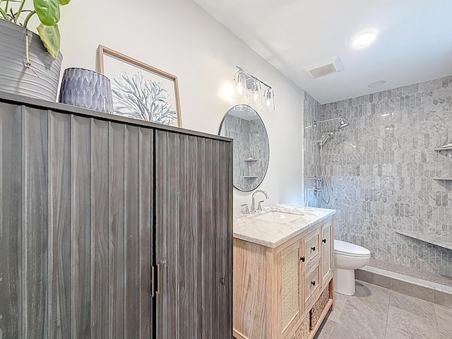 full bathroom featuring toilet, visible vents, a tile shower, and vanity