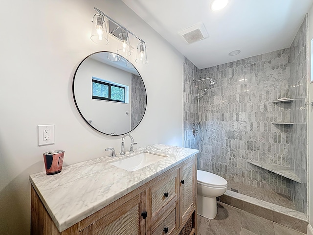 full bathroom with vanity, toilet, tiled shower, and visible vents