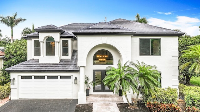 french country home with stucco siding, driveway, and a garage