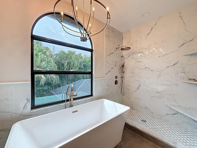 bathroom featuring a notable chandelier, tile walls, a marble finish shower, and a freestanding bath