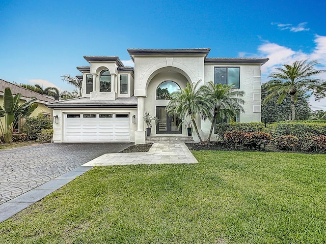 mediterranean / spanish-style home with a tiled roof, decorative driveway, stucco siding, and a garage