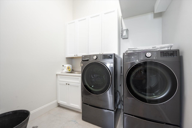 clothes washing area featuring independent washer and dryer, baseboards, and cabinet space