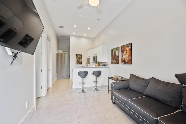 living room with a towering ceiling, visible vents, recessed lighting, light tile patterned flooring, and baseboards