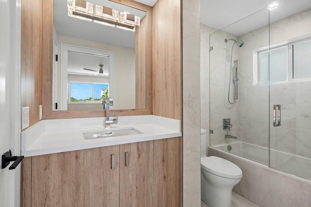 bathroom featuring enclosed tub / shower combo, toilet, and vanity