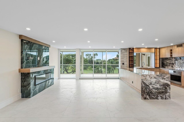 kitchen with stainless steel oven, modern cabinets, stone counters, and recessed lighting