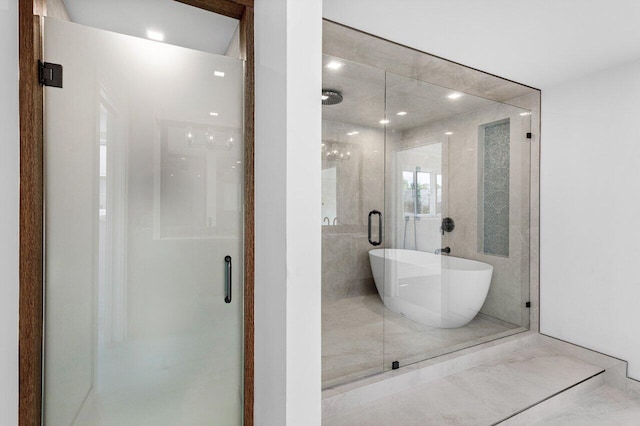 full bathroom featuring a freestanding tub, marble finish floor, and a shower stall