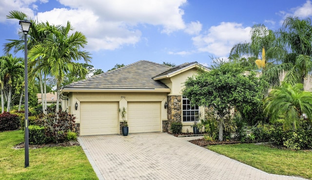 view of front of home featuring stone siding, stucco siding, an attached garage, driveway, and a front yard