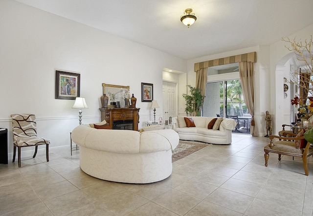 living room featuring light tile patterned flooring, a glass covered fireplace, and arched walkways