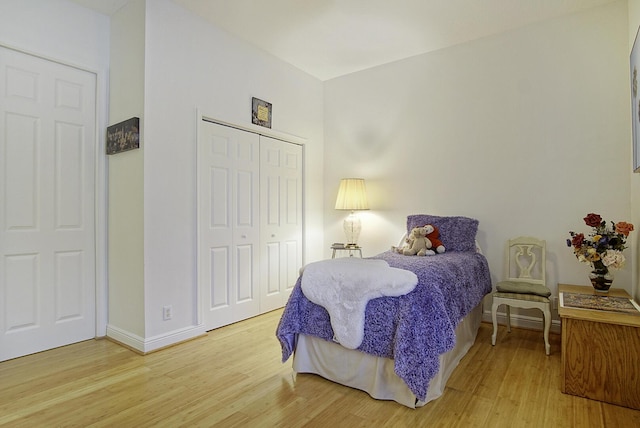 bedroom with wood finished floors, a closet, and baseboards