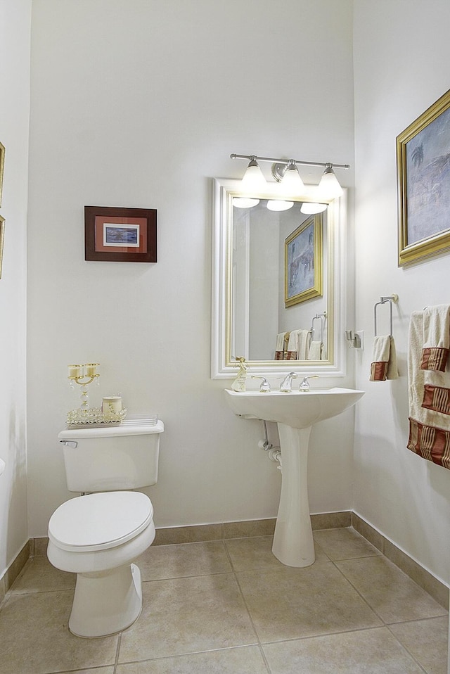 half bathroom with toilet, tile patterned floors, and baseboards