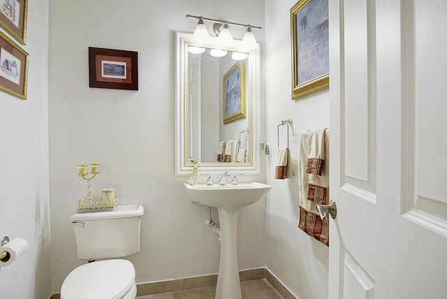 half bath with toilet, tile patterned floors, and baseboards