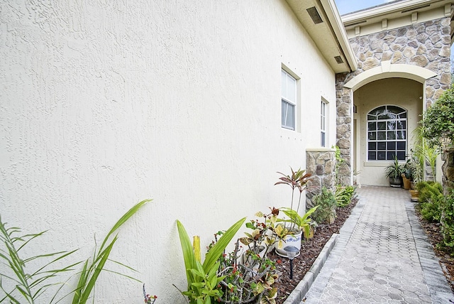 property entrance with stucco siding and stone siding