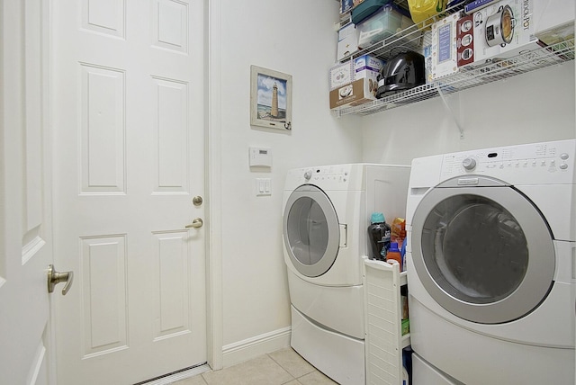washroom featuring washer and dryer, light tile patterned flooring, and baseboards