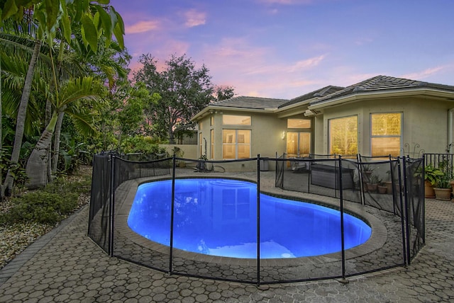 pool at dusk featuring french doors, a patio, and fence