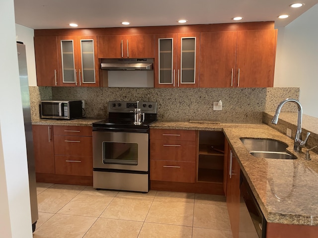 kitchen featuring tasteful backsplash, a sink, appliances with stainless steel finishes, under cabinet range hood, and stone counters
