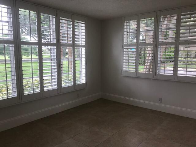 tiled empty room featuring baseboards and a textured ceiling