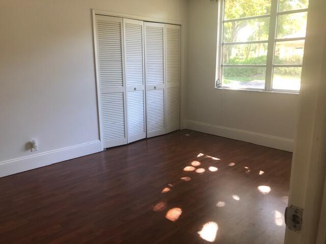 unfurnished bedroom featuring a closet, dark wood-style flooring, and baseboards
