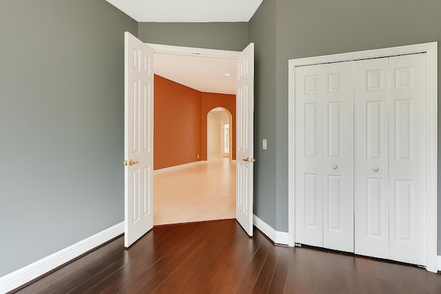 21504 Halstead Dr, Boca Raton, FL 33428 - unfurnished bedroom with arched walkways, baseboards, dark wood-style flooring, and a closet